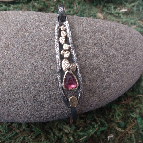 Our one-of-a-kind Rhodolite Pond Bracelet, features a hinged loop clasp, which swings up for sliding into, then down to lock into place.   Hand fabricated in textured oxidized sterling silver and 18k yellow gold   Metals: Oxidized sterling silver and 18k yellow gold Stones: Rhodolite