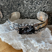 Load image into Gallery viewer, Hammered sterling silver cuff set with Silkote Alin meteorite in an industrial style including textured metal and silver “rivets.”

