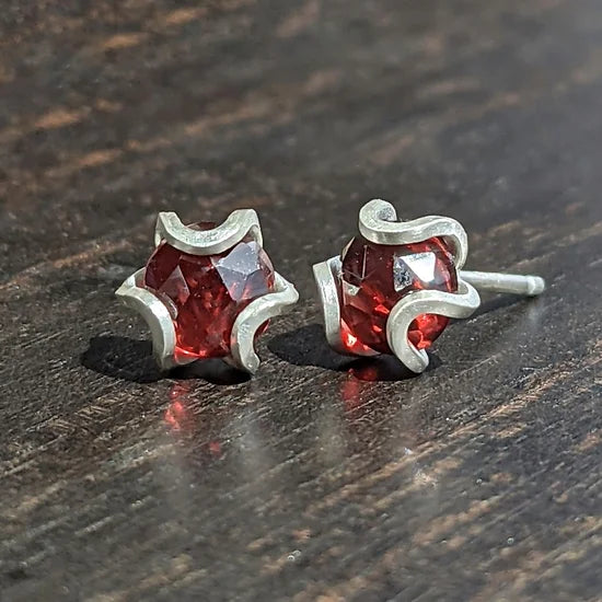 Iris studs in a medium size.    Geometric flowers with ethically sourced natural rose-cut gemstones. Each is individually hand fabricated.  Materials and Dimensions:  Garnets, natural and untreated, Mozambque origin  This size is slightly larger than the original version with 5mm faceted gems.  These come with comfy silicone covered silver butterfly backs