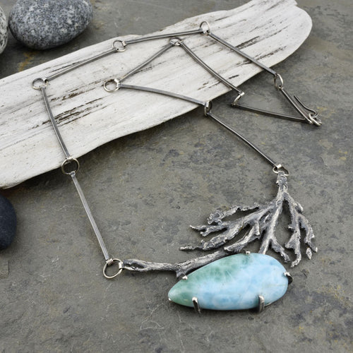 A prong-set larimar stone hangs from a frond of seaweed cast in sterling silver. A geometric bar chain completes this unusual statement piece.  This necklace embodies the drift of ocean current. The interplay of light blue, green, and white in the teardrop-shaped larimar is reminiscent of sea spray and breaking waves. When light hits the cast seaweed, it appears to sway softly.  This necklace pairs beautifully with the larimar and seaweed earrings.