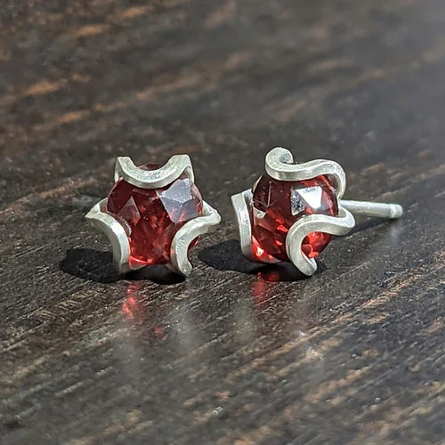 Iris studs in a medium size.    Geometric flowers with ethically sourced natural rose-cut gemstones. Each is individually hand fabricated.  Materials and Dimensions:  Garnets, natural and untreated, Mozambque origin  This size is slightly larger than the original version with 5mm faceted gems.  These come with comfy silicone covered silver butterfly backs. Unique gift for her for anniversary, birthday or Valentine's Day. Chester Springs, PA. 