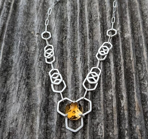 A Glowing Citrine Stone is set atop of a fused hexagon in this handmade chain necklace  Each link is fused and hammered multiple times before fusing into honeycomb chain links with a shimmery molten metal texture.  Handcrafted out of solid argentium silver, a tarnish resistant and hypoallergenic silver alloy.  One of a Kind.  Material: Solid Argentium Silver  Stone: Ethically sourced Citrine
